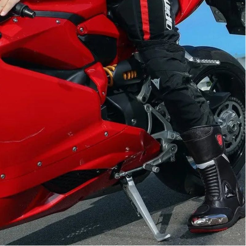 Person in racing gear sitting on a red motorcycle with a clear blue sky background