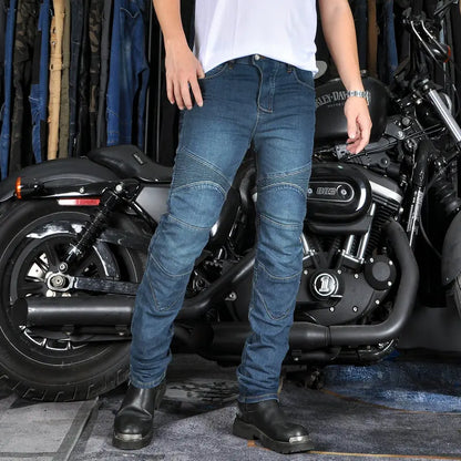Person wearing blue jeans and black shoes standing in front of a motorcycle.