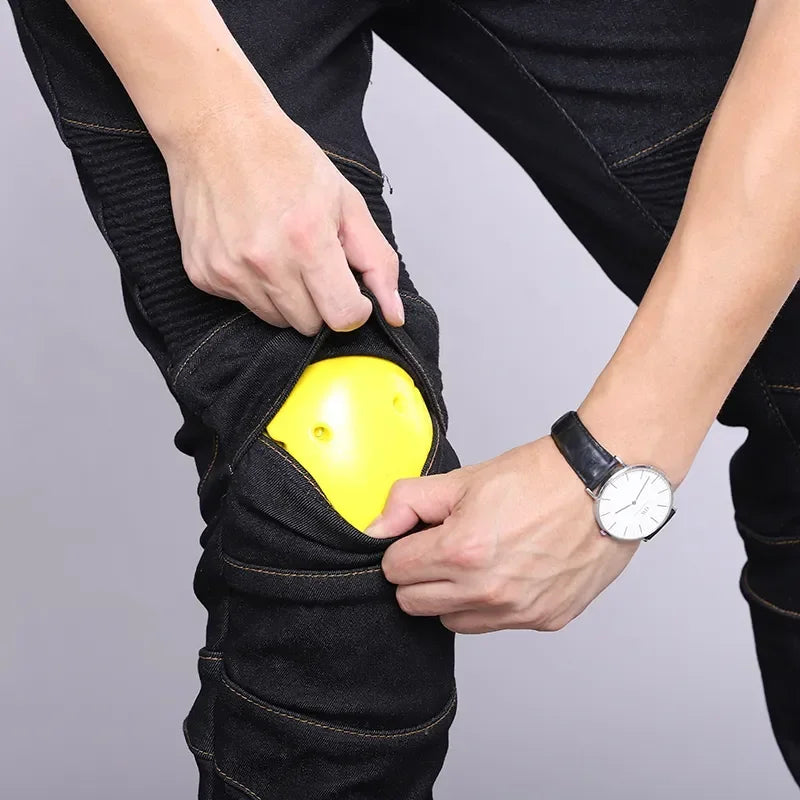 Person wearing black jeans with a yellow knee pad on a gray background