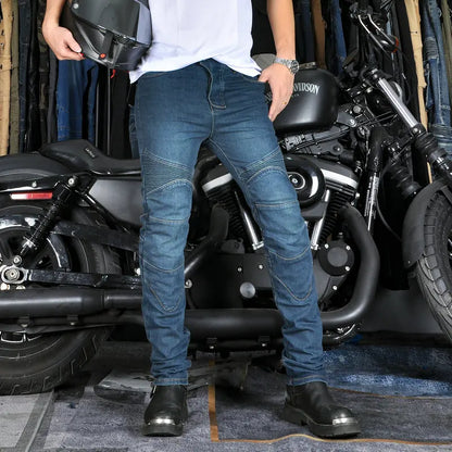 Person wearing blue jeans and black shoes standing next to a motorcycle in a garage.
