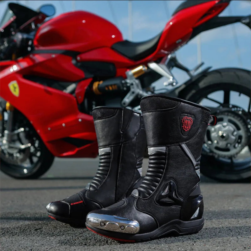 Black motorcycle boots with a red logo on a road with a red motorcycle in the background